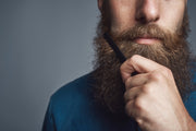 Close-up of a bearded man applying grooming product to his beard, emphasizing beard care and preparation for spring.